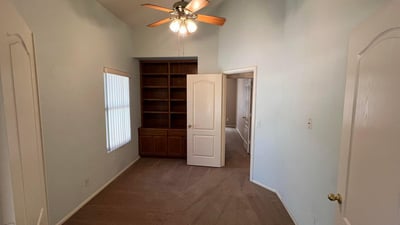 Flexible den enhanced by custom built-in shelving and vaulted ceilings. Ideal as a home office, study area, reading room, or hobby space while adding versatility to the home's layout.