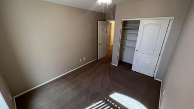 Inviting secondary bedroom with plush carpeting, ceiling fan, and neutral finishes. Natural light and a practical layout create a comfortable space for guests, family, or remote work.
