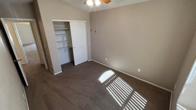 Spacious bedroom featuring a large closet, soft neutral tones, and ceiling fan. This versatile room offers flexibility for sleeping quarters, a hobby room, or a dedicated office space.