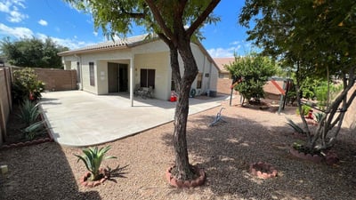 Inviting backyard with mature trees, desert landscaping, and a spacious covered patio. The thoughtfully designed outdoor space provides shade, privacy, and plenty of room for gatherings, recreation, or peaceful relaxation.