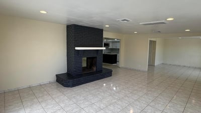 Open-concept family room showcasing a statement fireplace and seamless connection to the kitchen. The spacious design supports comfortable daily living and effortless entertaining.
