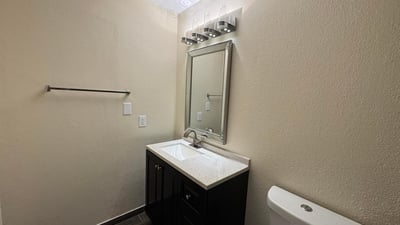 Updated half bathroom featuring contemporary fixtures, a sleek vanity, upgraded lighting, and attractive flooring. This refreshed space adds convenience and modern appeal to the home.