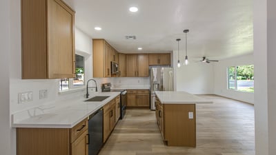 An open-concept design pairs abundant cabinetry, quartz surfaces, stainless steel appliances, and stylish lighting to create the perfect kitchen for cooking and gathering.