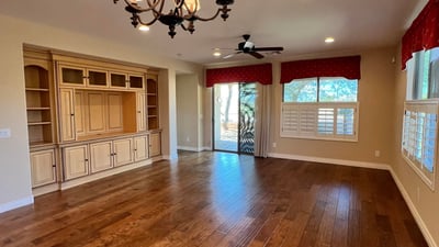 Expansive living room featuring custom built-in cabinetry, upgraded wood floors, elegant chandelier, recessed lighting, and abundant natural light. A warm and inviting gathering space designed for comfortable everyday living.