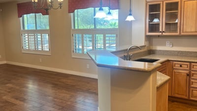 Inviting open-concept kitchen and dining area with custom cabinetry, breakfast bar, pendant lighting, plantation shutters, and upgraded flooring that creates a bright, welcoming atmosphere perfect for entertaining.