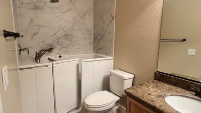 Well-appointed guest bathroom featuring a convenient walk-in tub, updated vanity, durable tile flooring, and attractive finishes that provide comfort, accessibility, and everyday functionality.