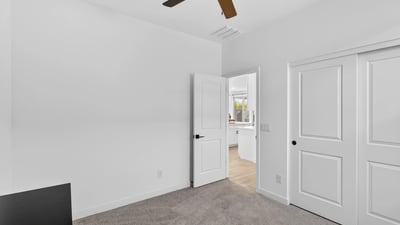 This spacious bedroom offers neutral finishes, soft carpeting, generous closet storage, and flexible living space perfect for family, guests, or a home office.