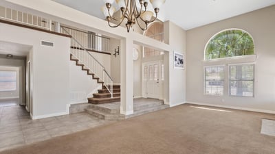 Architectural columns, dramatic ceiling heights, and an elegant staircase create a spacious, open feel throughout the main living area. The layout flows naturally into adjoining rooms for effortless entertaining.