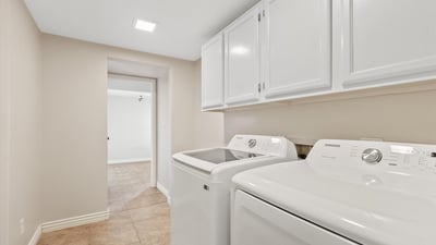 This well-appointed laundry room includes upper cabinetry, modern appliances, and additional storage to simplify daily routines. Conveniently located within the home's practical floor plan.