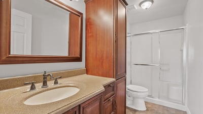 Updated cabinetry, modern fixtures, framed mirror, and a sliding glass shower enclosure create a clean and functional bathroom serving the secondary living spaces.