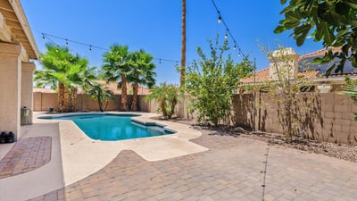 Wide paver patios, lush landscaping, and a sparkling pool create a welcoming outdoor space for gatherings, dining, and enjoying Arizona's beautiful weather in Chandler.