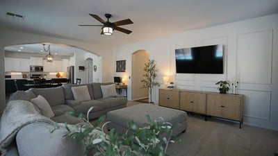 Beautiful family room with custom wall accents, plush carpeting, and an open layout connecting effortlessly to the kitchen. A welcoming space designed for relaxing and spending time together.