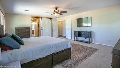 Comfortable primary bedroom with expansive floor space, plush carpeting, entertainment area, and convenient access to the luxurious en-suite bathroom. Designed for everyday comfort in Waddell.