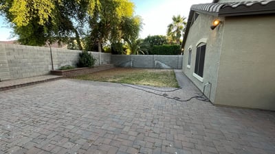 Generous backyard offers a spacious paver patio, grassy area, raised planter beds, and privacy walls, providing endless possibilities for entertaining or outdoor enjoyment.