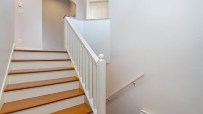 This inviting staircase features wooden steps and natural light, leading to additional living spaces upstairs.