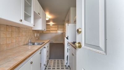 Spacious kitchen with ample cabinetry and tile countertops, leading into an inviting, open living space.