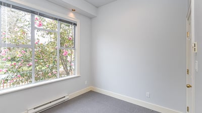 Bright room featuring a large window that offers natural light and views of blooming greenery.