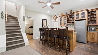 Spacious entertainment area featuring a modern kitchen bar with ample seating and convenient staircase access.