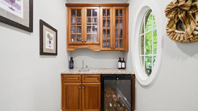 Perfect for entertaining, this cozy wine nook features stylish cabinetry and a compact fridge for easy access.