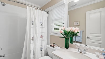 Bright bathroom featuring modern fixtures, a tub-shower combo, and fresh flowers enhancing the inviting atmosphere.