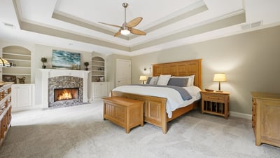 This spacious master bedroom features vaulted ceilings, a cozy fireplace, and ample built-in storage solutions.