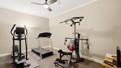 Spacious workout room featuring modern fitness equipment and ample natural light, perfect for home exercise routines.