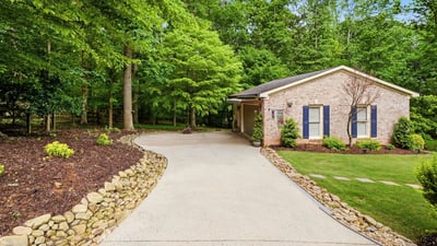 Discover a welcoming home nestled among lush greenery, featuring a spacious driveway and inviting outdoor spaces.