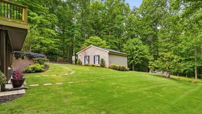 Nestled among lush trees, this property features expansive green space and a versatile outbuilding.