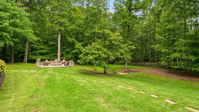 Spacious backyard with a cozy fire pit surrounded by lush greenery, perfect for gatherings and relaxation.