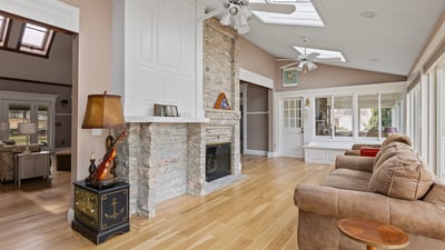 Bright and airy living space featuring a stone fireplace and large windows, perfect for entertaining or relaxing.