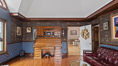 Spacious living area featuring distinctive woodwork, a classic desk, and inviting natural light throughout.
