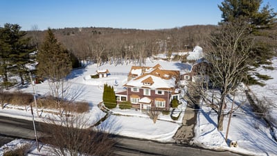 Spacious home nestled in a snowy landscape, featuring ample outdoor space and convenient access to the road.