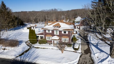 Spacious home on a large lot, featuring expansive outdoor areas and nearby wooded surroundings.