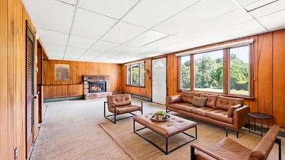 Spacious living area featuring ample natural light, a cozy fireplace, and views of the surrounding greenery.