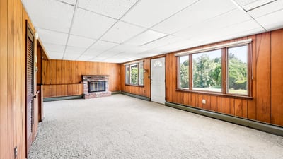 Spacious living area with abundant natural light, featuring wood paneling and cozy fireplace, ready for personalization.