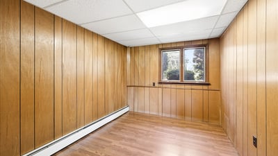 Spacious room with warm wooden paneling, offering natural light and potential for customization.