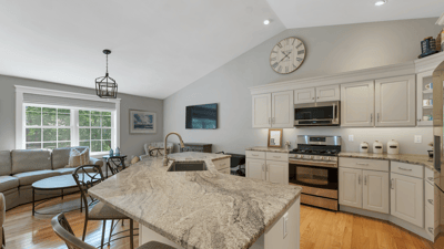 Modern kitchen featuring high ceilings, granite countertops, and spacious living area with abundant natural light.