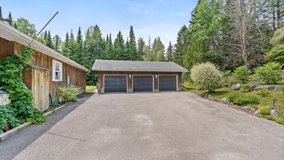 Spacious property featuring ample parking and garage space, surrounded by lush greenery and natural beauty.