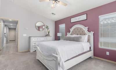 Unwind in the spacious primary suite offering plush carpet, large windows, neutral colors, and generous room for a sitting area or additional furnishings, creating a relaxing retreat.