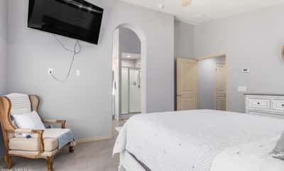 The spacious primary bedroom offers plush carpeting, a ceiling fan, neutral finishes, and convenient access to the ensuite bathroom. A peaceful retreat designed for comfort and relaxation.