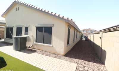 The home's side yard showcases easy-care desert landscaping, paver pathways, and convenient access around the property, providing attractive curb appeal with minimal maintenance in Buckeye.
