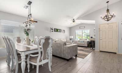 The open floor plan effortlessly connects the dining and living areas, creating an inviting atmosphere enhanced by modern flooring, designer lighting, and abundant natural light throughout.