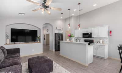 The stylish kitchen showcases white quartz countertops, white cabinetry, recessed lighting, a spacious breakfast bar, and open sightlines to the family room, making meal preparation and entertaining easy.