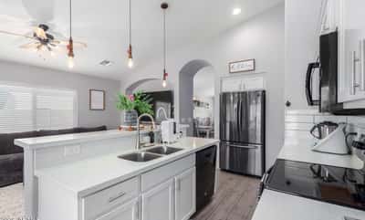 White quartz countertops, crisp white cabinetry, a spacious breakfast bar, and an open floor plan make this stylish kitchen the heart of the home. Perfect for entertaining and everyday living.