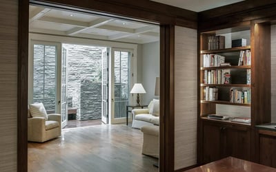 Modern living space featuring a cozy reading nook, dual access to a serene outdoor patio, and elegant finishes.