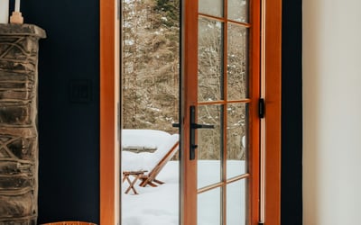 Bright entryway featuring a wooden door opening to a snowy outdoor retreat, perfect for winter getaways.