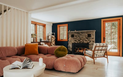 Cozy living room featuring a unique stone fireplace, modern furniture, and large windows for natural light.