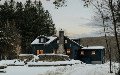 Discover this beautiful mountain retreat, featuring a stone chimney and picturesque winter landscape, perfect for cozy getaways.