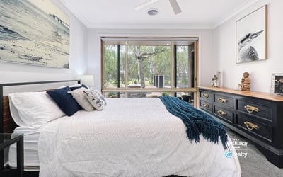Spacious bedroom featuring large windows, natural light, and a view of lush outdoor greenery.