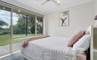 Bright and airy bedroom with large windows offering stunning views of the lush backyard.